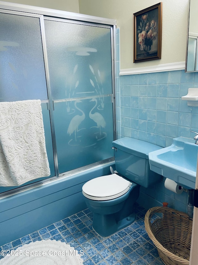 full bathroom featuring combined bath / shower with glass door, tile walls, tile patterned floors, and toilet