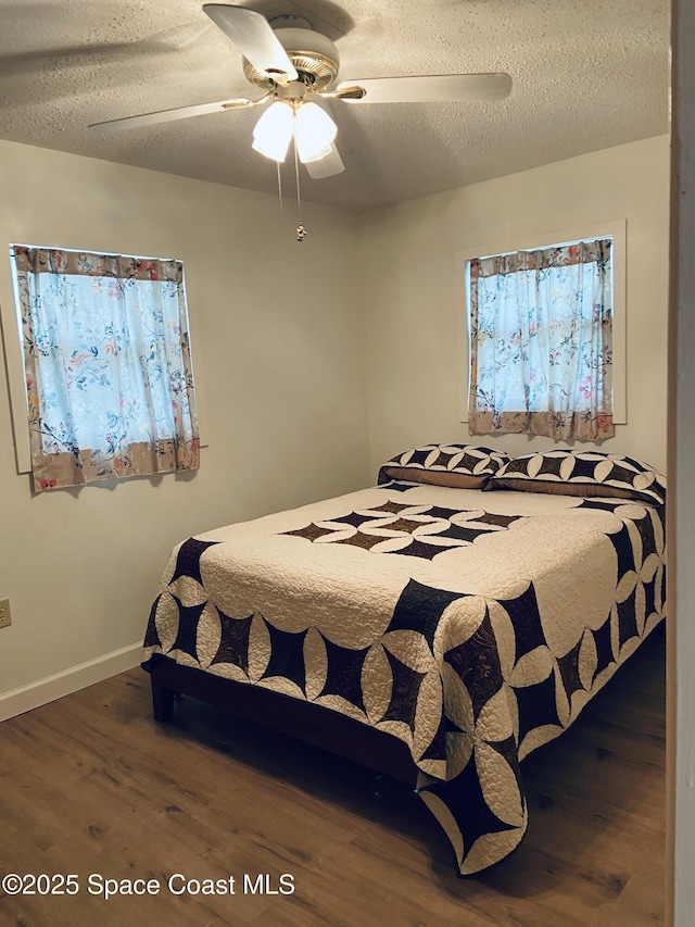 bedroom featuring ceiling fan, dark hardwood / wood-style floors, and a textured ceiling