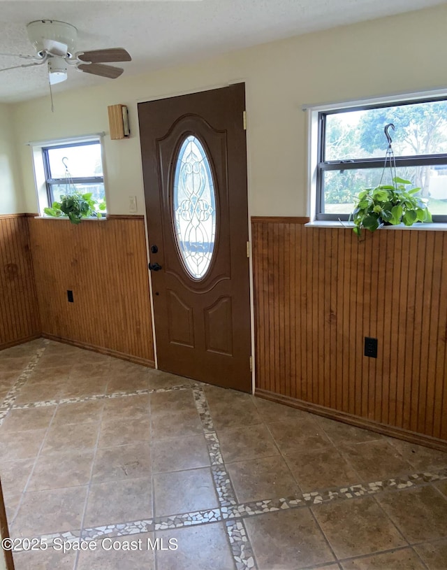 entryway featuring ceiling fan and wood walls