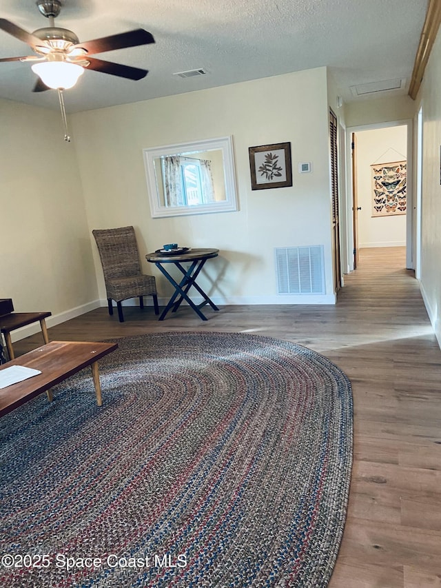 sitting room with ceiling fan, a textured ceiling, and light hardwood / wood-style floors