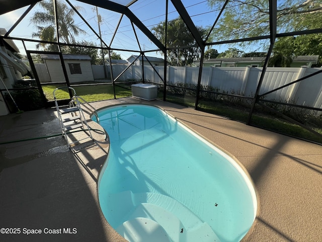 view of pool featuring a patio, a yard, glass enclosure, and a storage unit