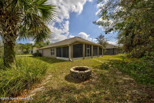 back of house with an outdoor fire pit, a yard, and a sunroom