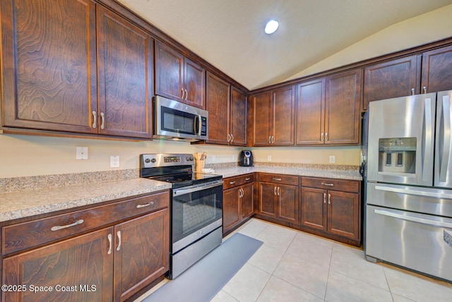 kitchen featuring vaulted ceiling, appliances with stainless steel finishes, light tile patterned floors, and dark brown cabinetry