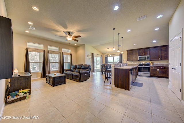 kitchen with a breakfast bar, decorative light fixtures, a kitchen island with sink, dark brown cabinetry, and stainless steel appliances