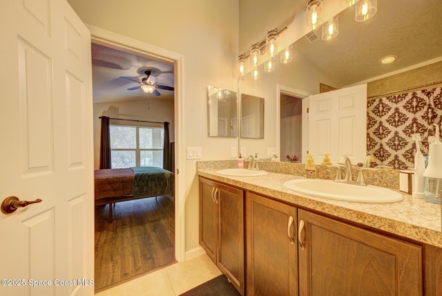 bathroom with lofted ceiling, tile patterned flooring, vanity, ceiling fan, and a textured ceiling