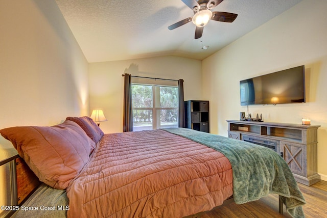 bedroom with ceiling fan, lofted ceiling, light hardwood / wood-style flooring, and a textured ceiling