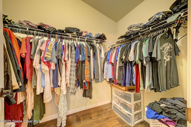 walk in closet with wood-type flooring and vaulted ceiling