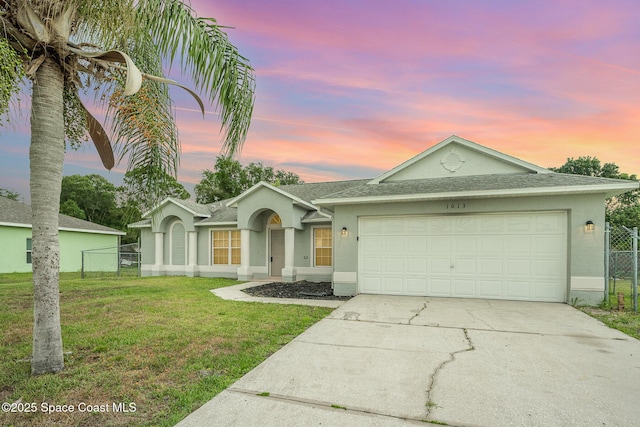 single story home featuring a garage and a lawn