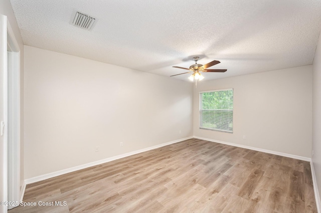 empty room featuring ceiling fan, light hardwood / wood-style flooring, and a textured ceiling