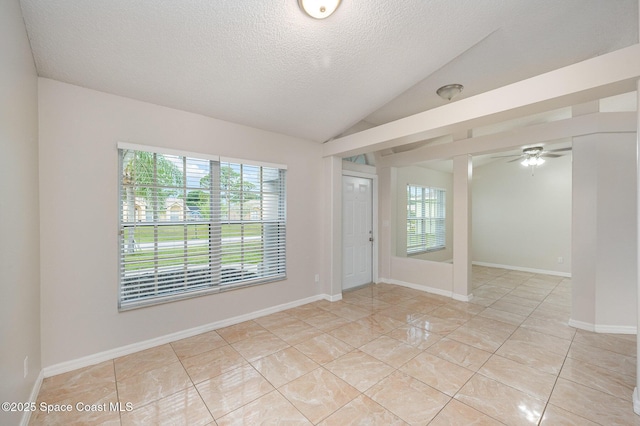 tiled spare room with ceiling fan, vaulted ceiling, a textured ceiling, and a wealth of natural light