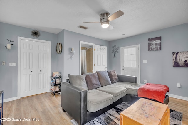 living room with ceiling fan, light hardwood / wood-style flooring, and a textured ceiling