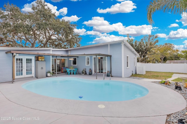 rear view of property with a fenced in pool, a patio area, and french doors