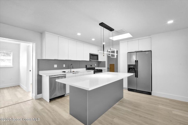 kitchen featuring sink, hanging light fixtures, stainless steel appliances, white cabinets, and a kitchen island