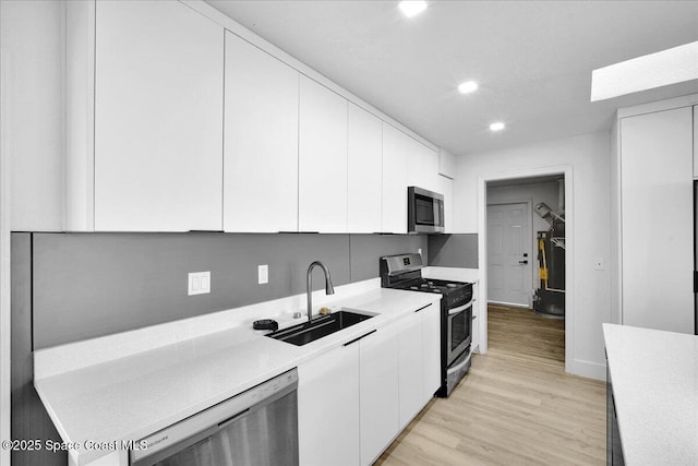 kitchen featuring light wood-type flooring, stainless steel appliances, sink, and white cabinets