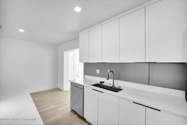 kitchen with dishwasher, sink, white cabinets, and light hardwood / wood-style flooring