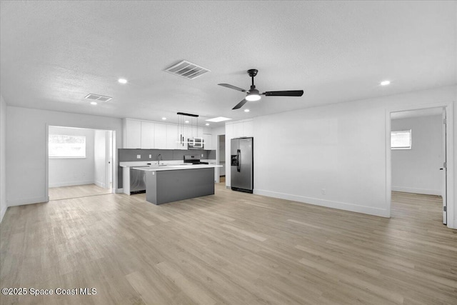 kitchen featuring a kitchen island, pendant lighting, white cabinets, stainless steel appliances, and light hardwood / wood-style flooring