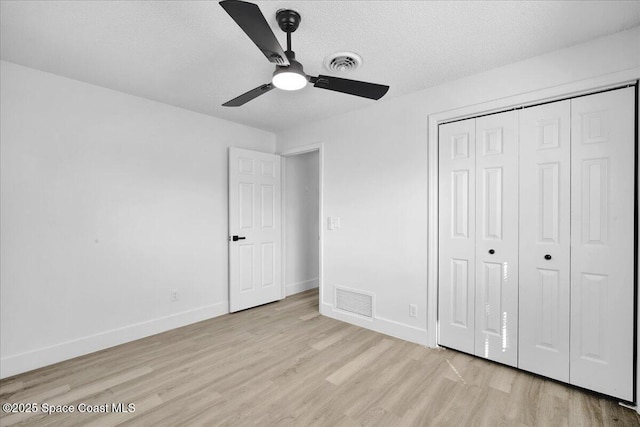 unfurnished bedroom featuring ceiling fan, a closet, light hardwood / wood-style flooring, and a textured ceiling