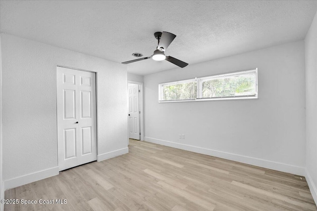 unfurnished bedroom with ceiling fan, a closet, a textured ceiling, and light wood-type flooring