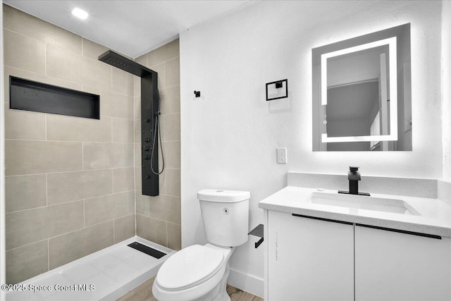 bathroom featuring vanity, toilet, and a tile shower