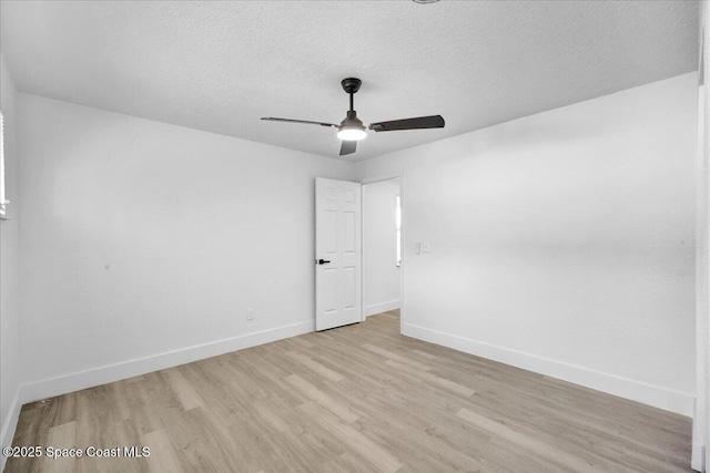 empty room with ceiling fan, a textured ceiling, and light wood-type flooring