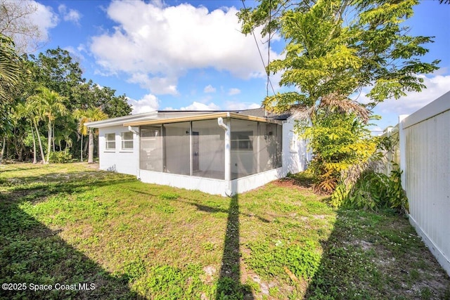 rear view of property with a sunroom and a lawn