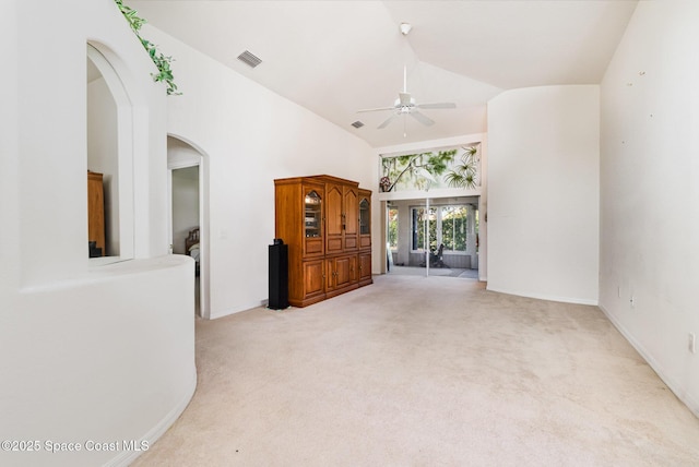 unfurnished room with visible vents, high vaulted ceiling, carpet floors, arched walkways, and ceiling fan