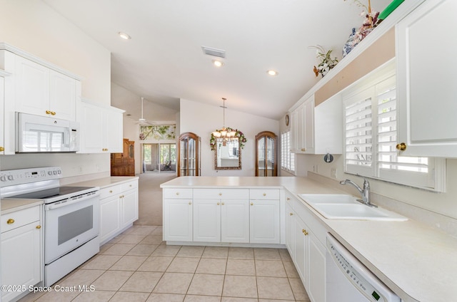 kitchen featuring white appliances, visible vents, a peninsula, a sink, and white cabinetry