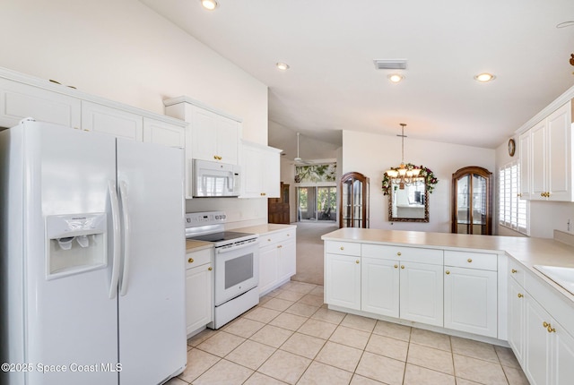 kitchen featuring visible vents, white appliances, a peninsula, light countertops, and vaulted ceiling