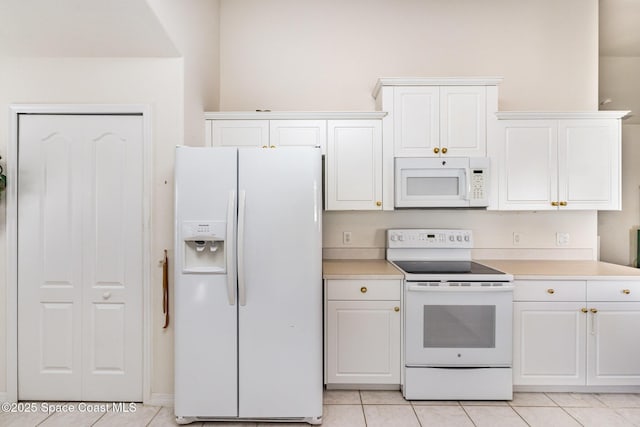 kitchen with light tile patterned floors, white appliances, white cabinets, and light countertops