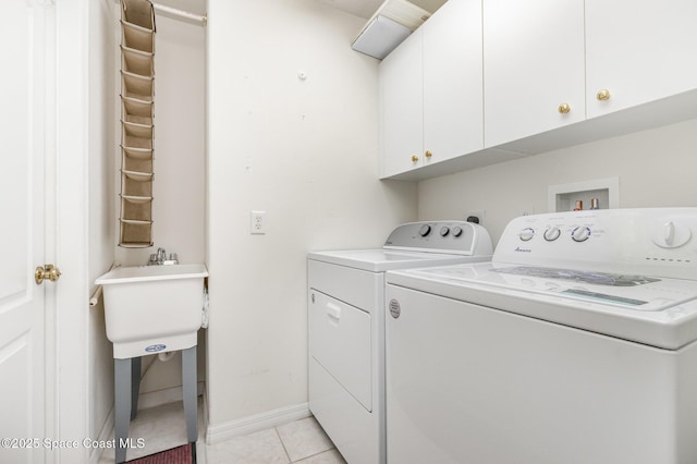 laundry room featuring light tile patterned floors, cabinet space, baseboards, and washer and clothes dryer