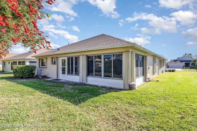 back of house featuring a yard, a sunroom, and a shingled roof