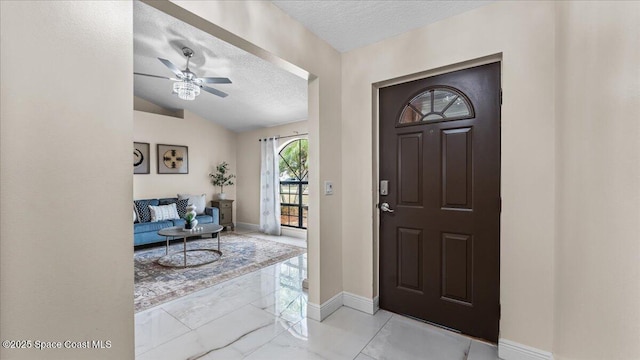 entryway featuring ceiling fan, lofted ceiling, and a textured ceiling