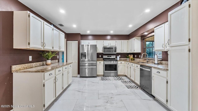 kitchen featuring light stone countertops, appliances with stainless steel finishes, sink, and white cabinets