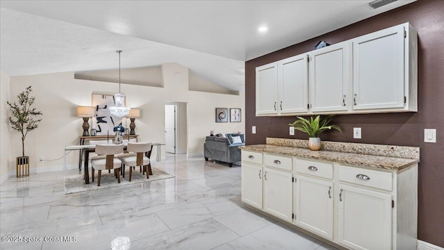 kitchen with white cabinetry, vaulted ceiling, light stone counters, and pendant lighting