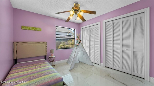 bedroom with ceiling fan, a textured ceiling, and multiple closets