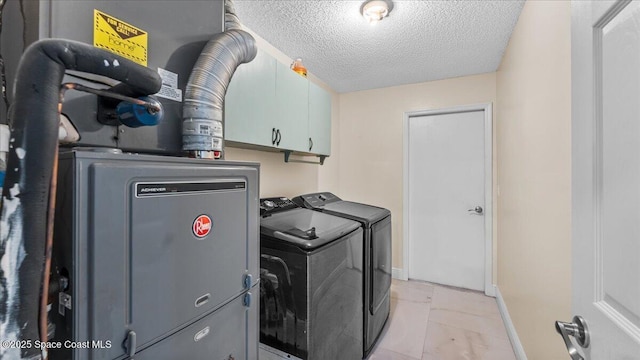 washroom featuring washer and clothes dryer, cabinets, and a textured ceiling