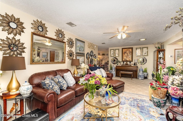 carpeted living room featuring ceiling fan and a textured ceiling