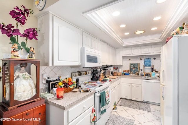 kitchen featuring white appliances, crown molding, white cabinetry, tasteful backsplash, and a raised ceiling