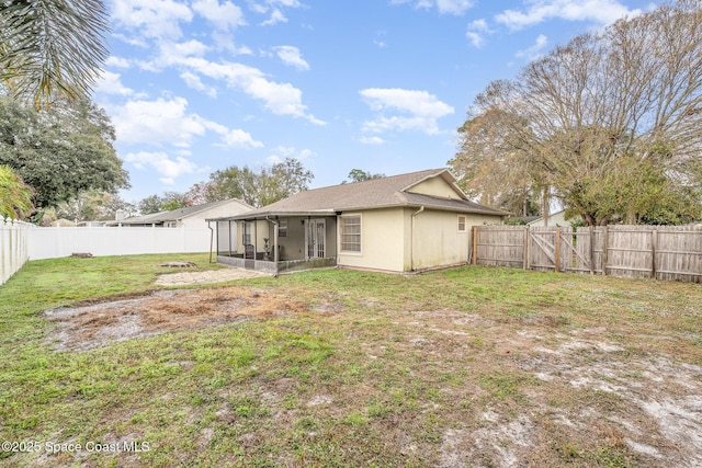 rear view of house featuring a sunroom and a lawn