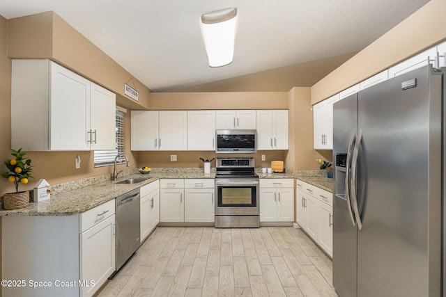 kitchen with sink, appliances with stainless steel finishes, white cabinetry, light stone counters, and light hardwood / wood-style floors