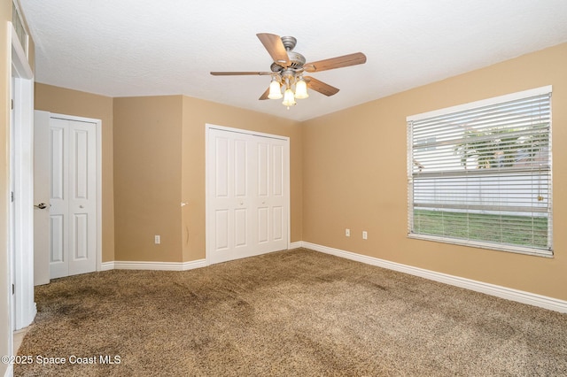 unfurnished bedroom featuring multiple closets, ceiling fan, carpet, and a textured ceiling