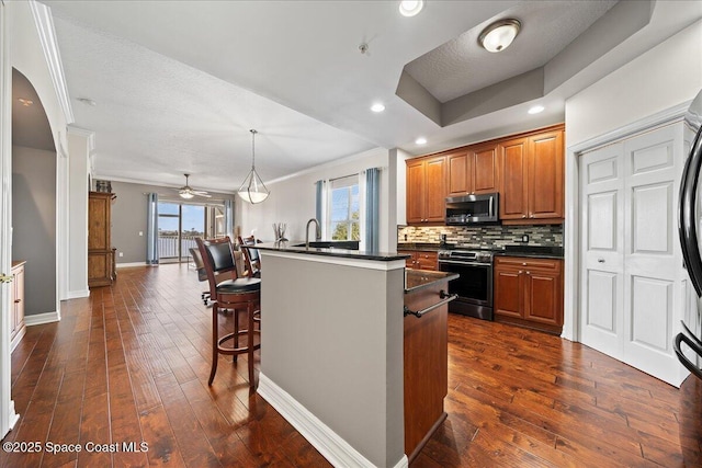 kitchen with appliances with stainless steel finishes, a center island, tasteful backsplash, a kitchen bar, and decorative light fixtures