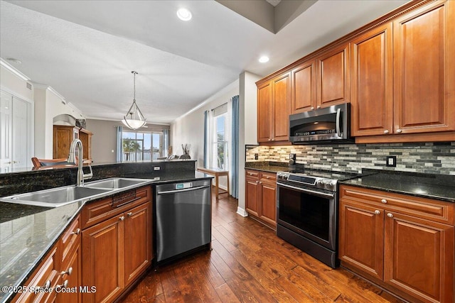 kitchen with pendant lighting, sink, appliances with stainless steel finishes, backsplash, and dark hardwood / wood-style flooring