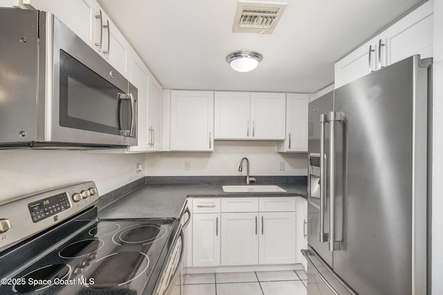 kitchen featuring white cabinetry, appliances with stainless steel finishes, sink, and light tile patterned floors