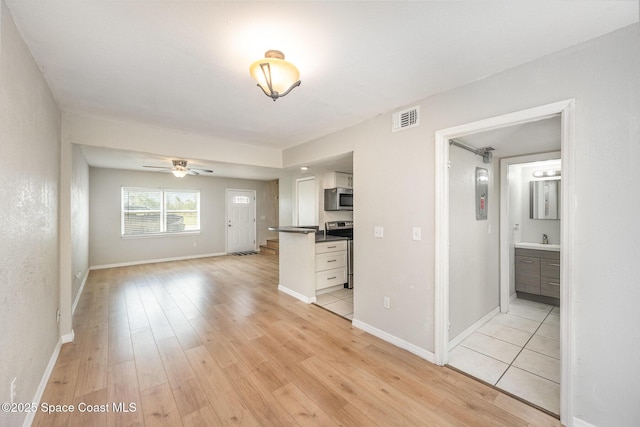 unfurnished living room featuring sink, light hardwood / wood-style flooring, and ceiling fan