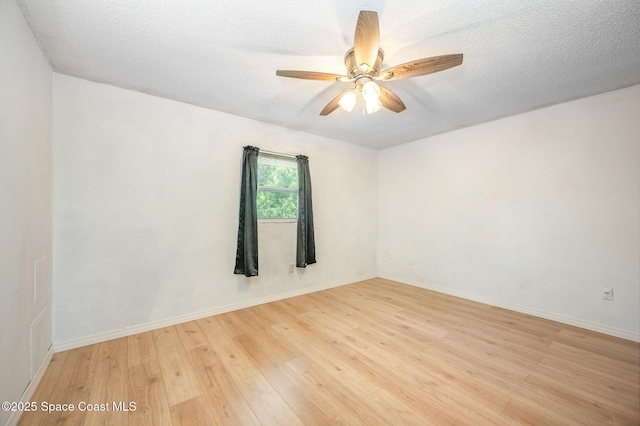 empty room with ceiling fan, a textured ceiling, and light wood-type flooring