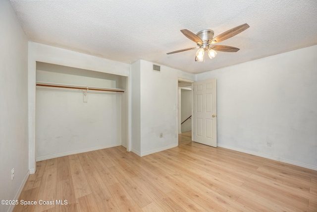 unfurnished bedroom with ceiling fan, a closet, a textured ceiling, and light wood-type flooring