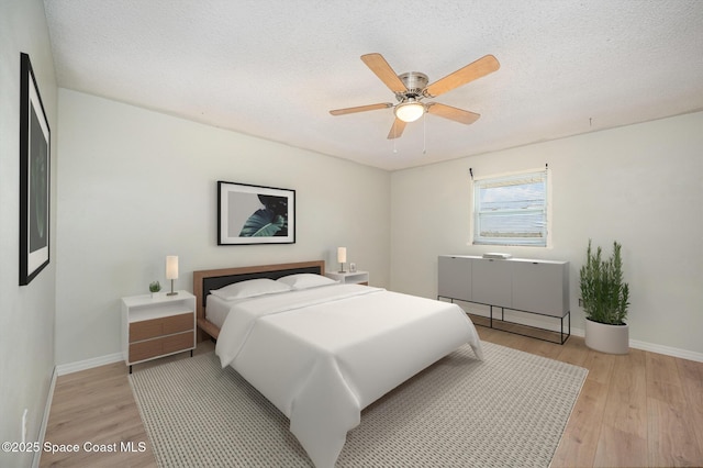 bedroom with ceiling fan, a textured ceiling, and light hardwood / wood-style floors