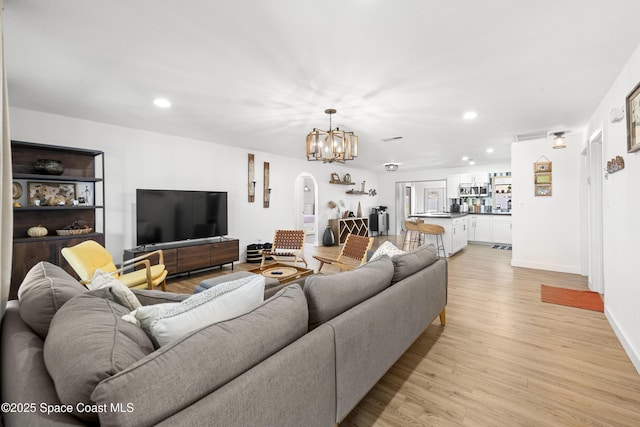 living room with an inviting chandelier and light wood-type flooring