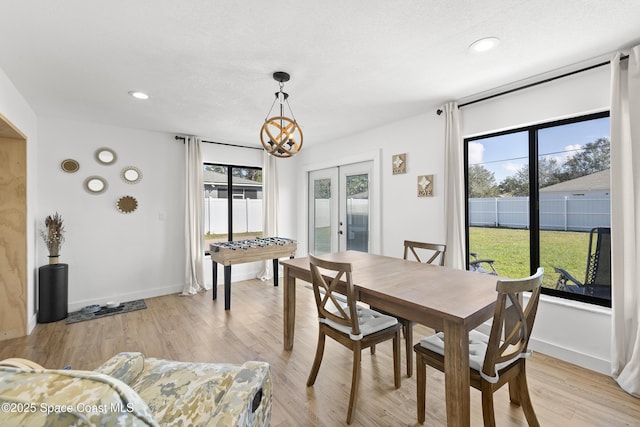 dining room featuring plenty of natural light, a chandelier, light wood-type flooring, and french doors